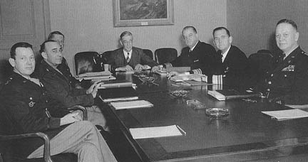 R&eacute;union du JRDB le 11 f&eacute;vrier 1948. On distingue de gauche &agrave; droite : le major-g&eacute;n&eacute;ral L. C. Craigie, le g&eacute;n&eacute;ral Joseph T. McNarney, le g&eacute;n&eacute;ral Jacob L. Devers, le docteur Vannevar Bush (pr&eacute;sident du JRBD), le vice-amiral E. W. Mills, le vice-admiral J. D. Price et le lieutenant-g&eacute;n&eacute;ral H. S. Arnold
