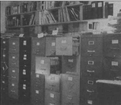 Les archives de cas et une partie de la bibliothèque de l'APRO à Alamogordo (Nouveau-Mexique) en 1955,    dans la 1ʳᵉ pièce dédiée à l'association, un garage réaménagé.