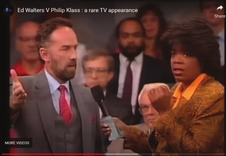 Ed Walters, debout et gesticulant, à côté d'Oprah Winfrey tenant un micro au milieu du public de son émission